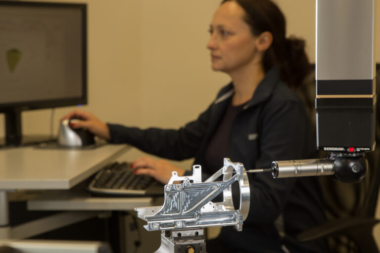 Women testing the quality of a part.