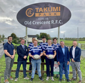 Old Crescent RFC grounds named Takumi Park image of new Takumi park sign and members of the club holding rugby balls